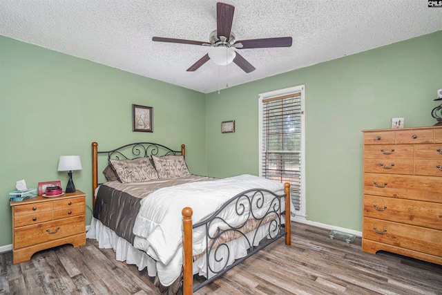 bedroom featuring ceiling fan, hardwood / wood-style floors, and a textured ceiling