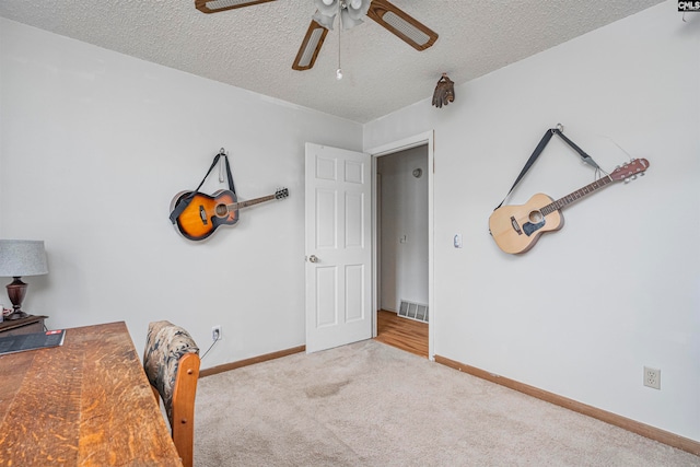 unfurnished office featuring ceiling fan, light colored carpet, and a textured ceiling