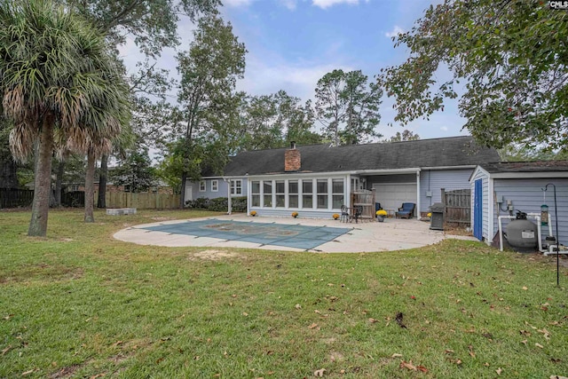 back of property with a yard, a covered pool, a patio area, and a sunroom