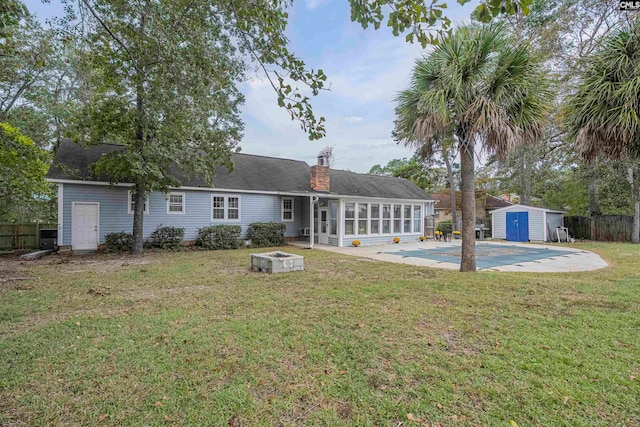 back of property with a lawn, a sunroom, a storage shed, and a covered pool