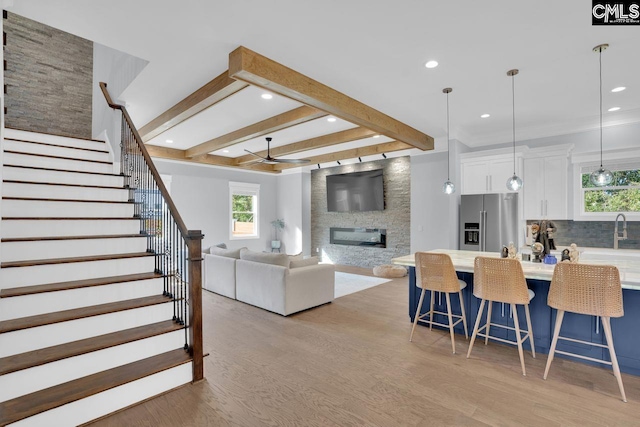 living room featuring light hardwood / wood-style floors, sink, a fireplace, and ceiling fan