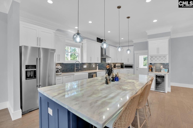 kitchen featuring a spacious island, appliances with stainless steel finishes, decorative light fixtures, and white cabinetry