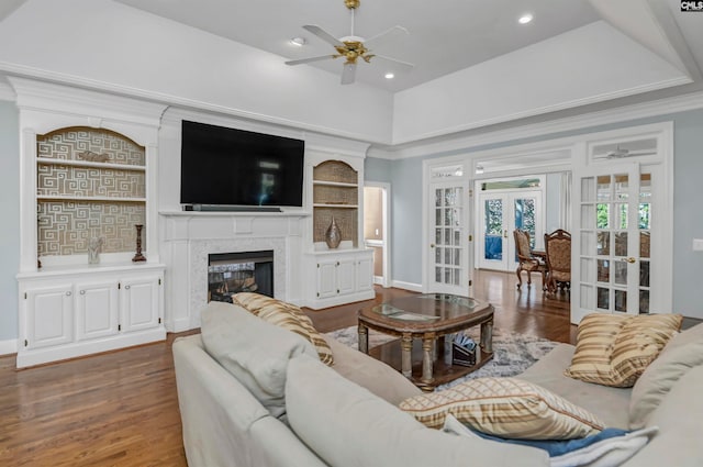 living room with dark hardwood / wood-style flooring, ceiling fan, a tray ceiling, a premium fireplace, and french doors