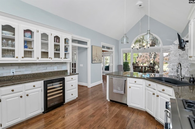 kitchen with stainless steel appliances, white cabinetry, beverage cooler, and backsplash