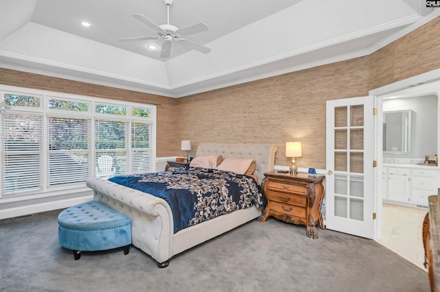 carpeted bedroom featuring ceiling fan, ensuite bath, a tray ceiling, and crown molding