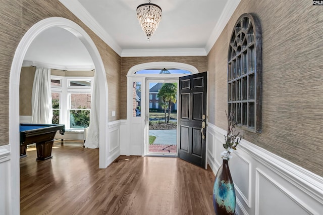 foyer entrance featuring dark wood-type flooring, billiards, crown molding, and an inviting chandelier