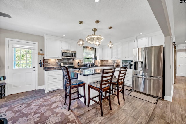 kitchen with hardwood / wood-style flooring, a healthy amount of sunlight, appliances with stainless steel finishes, and white cabinets