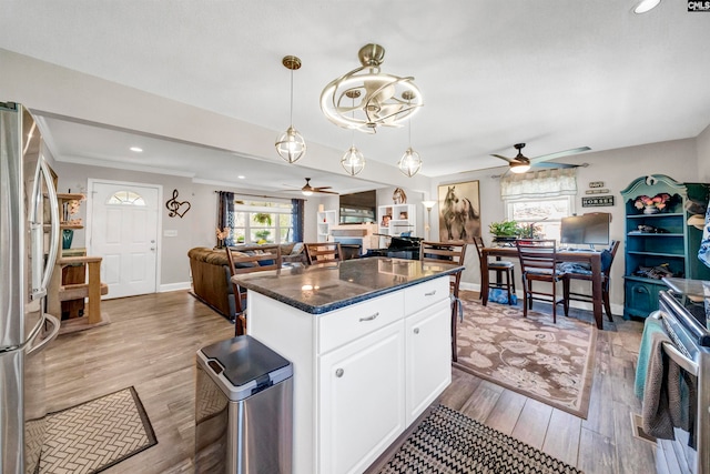 kitchen featuring light wood-type flooring, a center island, hanging light fixtures, white cabinetry, and stainless steel appliances