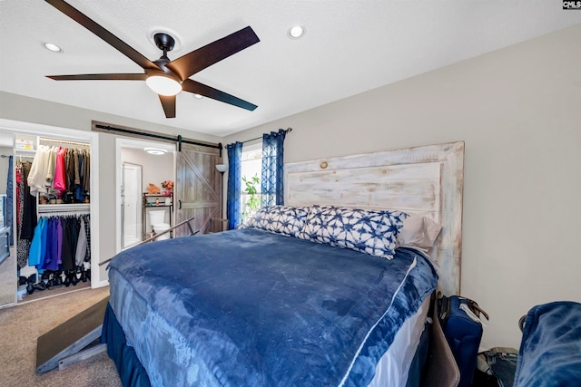 carpeted bedroom with a closet, a barn door, and ceiling fan