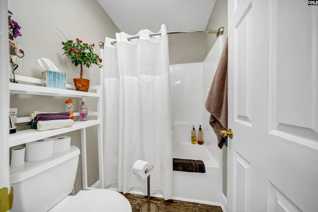 bathroom featuring toilet, hardwood / wood-style flooring, shower / bath combo with shower curtain, and a textured ceiling