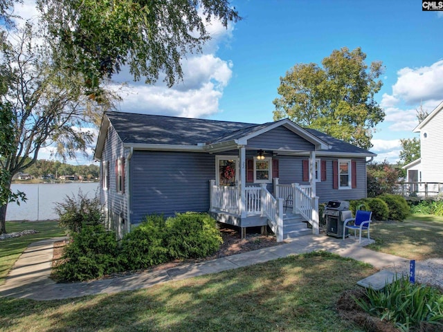 view of front of house with a water view, ceiling fan, and a front lawn