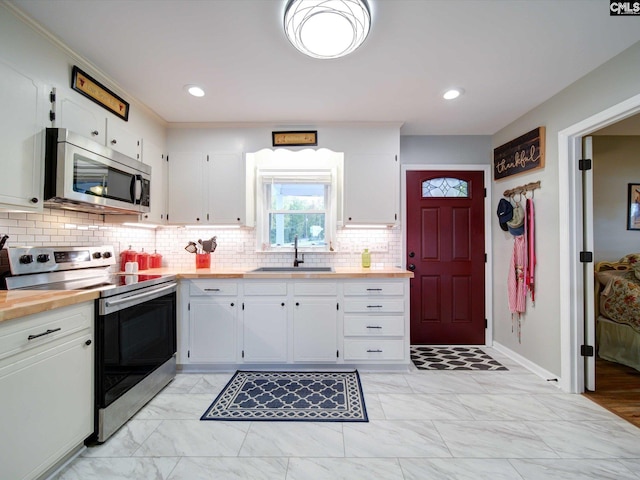 kitchen with white cabinets, stainless steel appliances, sink, and wood counters