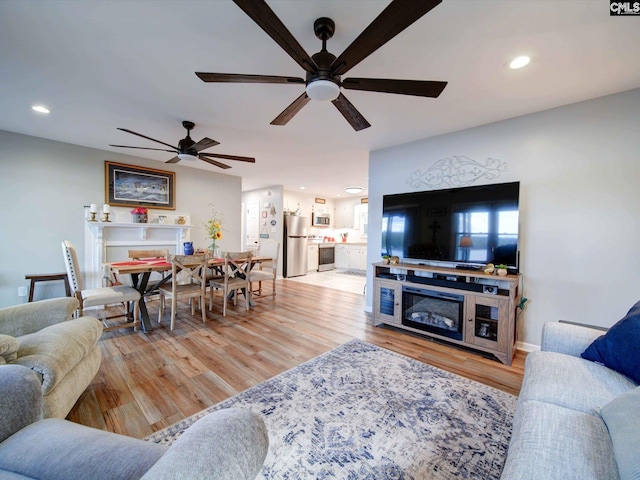 living room with light hardwood / wood-style flooring and ceiling fan