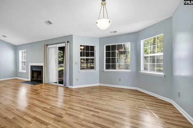 unfurnished living room with a textured ceiling and light wood-type flooring