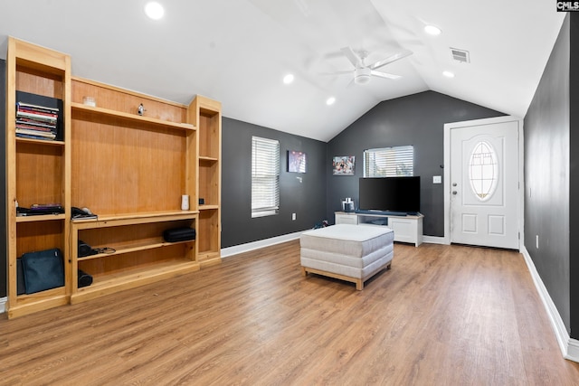 living room with hardwood / wood-style flooring, ceiling fan, and vaulted ceiling