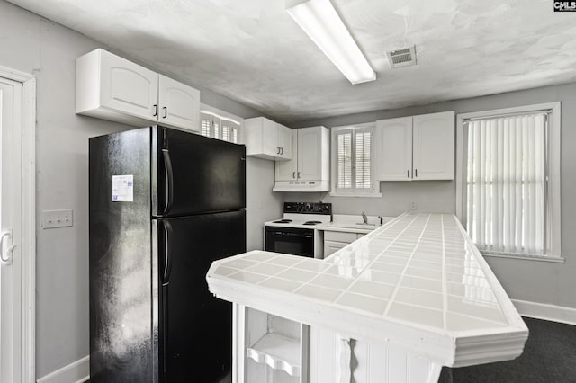 6560 Voorhees Rd, Denmark, SC 29042 - kitchen with freestanding refrigerator, white electric range, under cabinet range hood, tile countertops, and white cabinetry