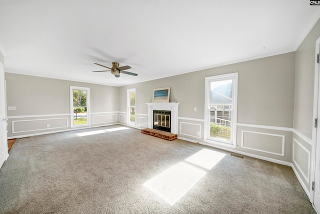 unfurnished living room with ornamental molding, carpet, a brick fireplace, and ceiling fan