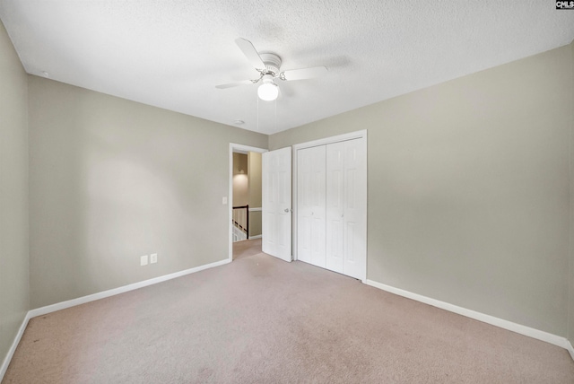 unfurnished bedroom featuring a closet, a textured ceiling, carpet, and ceiling fan