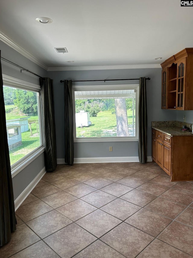 unfurnished dining area with light tile patterned flooring, ornamental molding, and a wealth of natural light