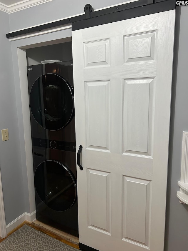 clothes washing area featuring stacked washer / dryer, crown molding, and wood-type flooring