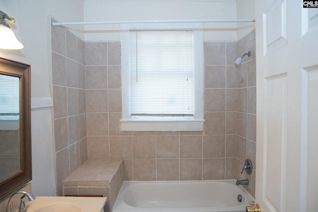 bathroom with vanity, tiled shower / bath combo, and tile walls