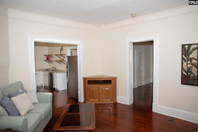 living room featuring dark wood-type flooring, ornamental molding, and sink