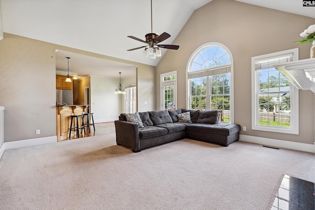 carpeted living room with ceiling fan with notable chandelier and high vaulted ceiling