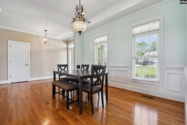 dining area with an inviting chandelier, ornamental molding, wood-type flooring, and plenty of natural light