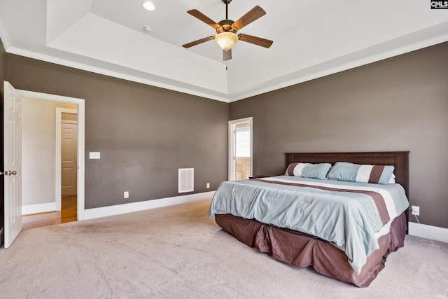 bedroom with crown molding, ceiling fan, light carpet, and a raised ceiling