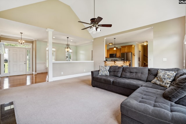 living room featuring ceiling fan, high vaulted ceiling, light wood-type flooring, decorative columns, and crown molding