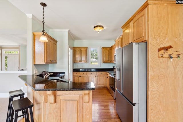 kitchen featuring kitchen peninsula, a breakfast bar area, hardwood / wood-style flooring, stainless steel appliances, and decorative light fixtures