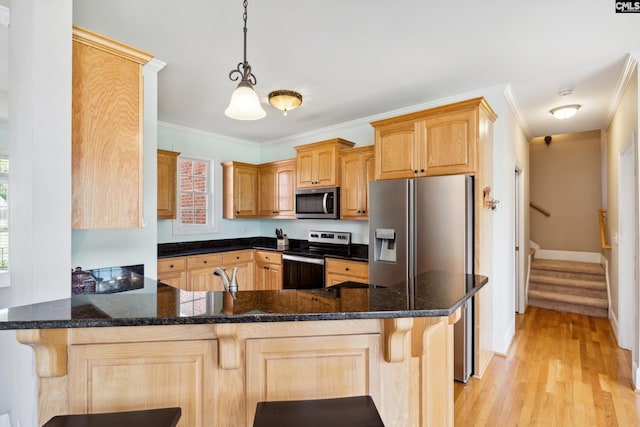 kitchen featuring kitchen peninsula, appliances with stainless steel finishes, ornamental molding, pendant lighting, and light hardwood / wood-style floors