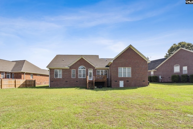 rear view of house with a wooden deck and a lawn