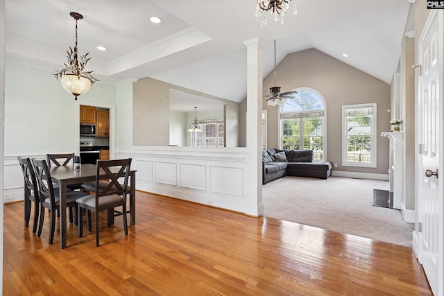 dining area featuring ornamental molding, light colored carpet, ceiling fan with notable chandelier, and vaulted ceiling