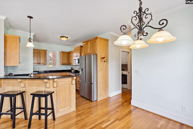 kitchen featuring appliances with stainless steel finishes, kitchen peninsula, pendant lighting, and light wood-type flooring