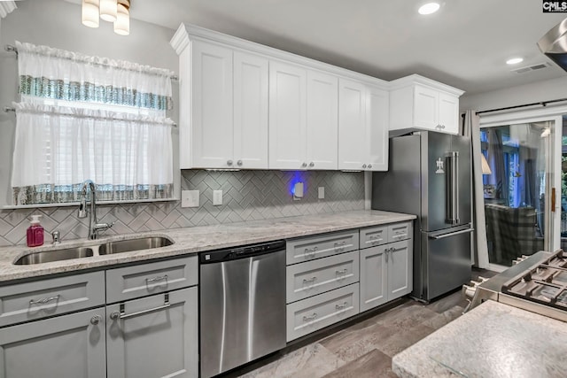 kitchen with tasteful backsplash, white cabinetry, sink, gray cabinetry, and stainless steel appliances