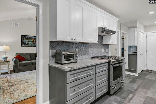 kitchen featuring high end stainless steel range oven, backsplash, vaulted ceiling, white cabinets, and light stone counters