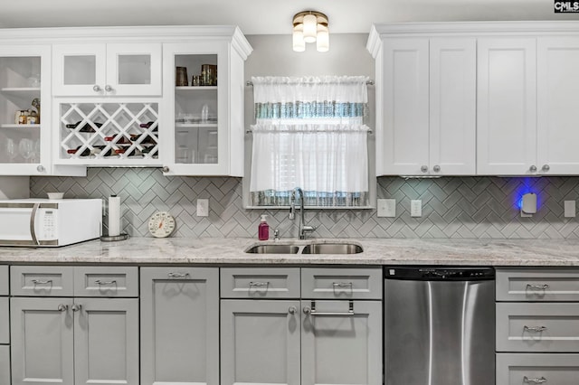 kitchen featuring decorative backsplash, light stone countertops, stainless steel dishwasher, and sink