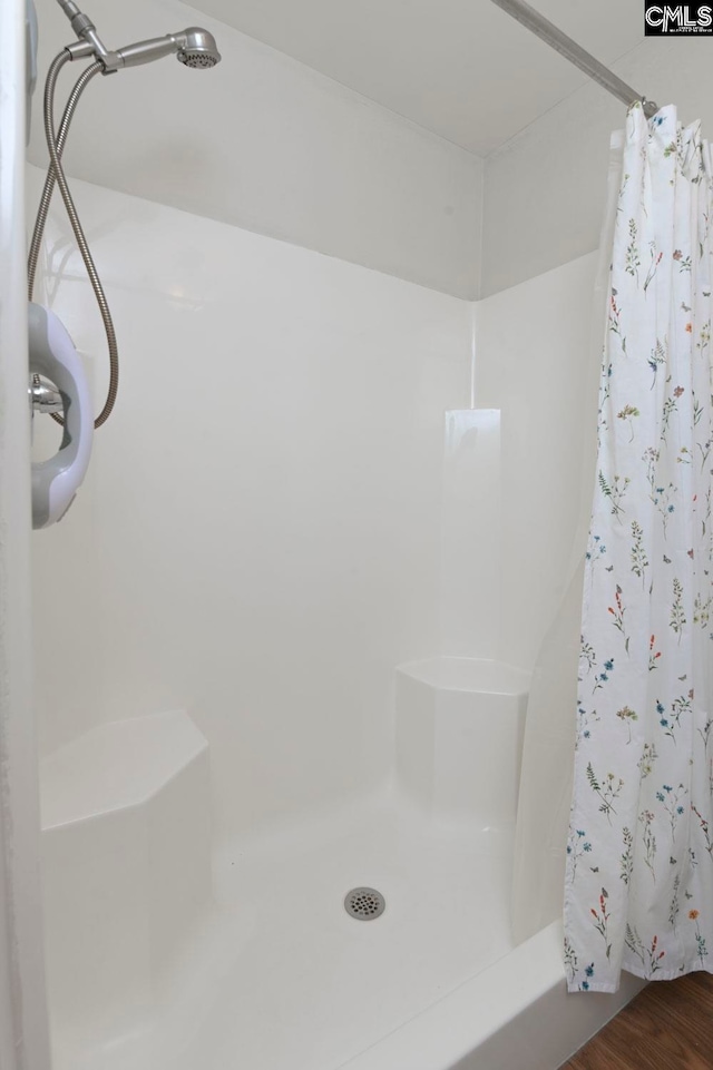 bathroom with a shower with shower curtain and hardwood / wood-style flooring