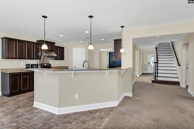 kitchen with black appliances, kitchen peninsula, decorative light fixtures, a breakfast bar area, and light colored carpet