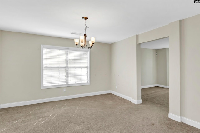 carpeted spare room with a chandelier