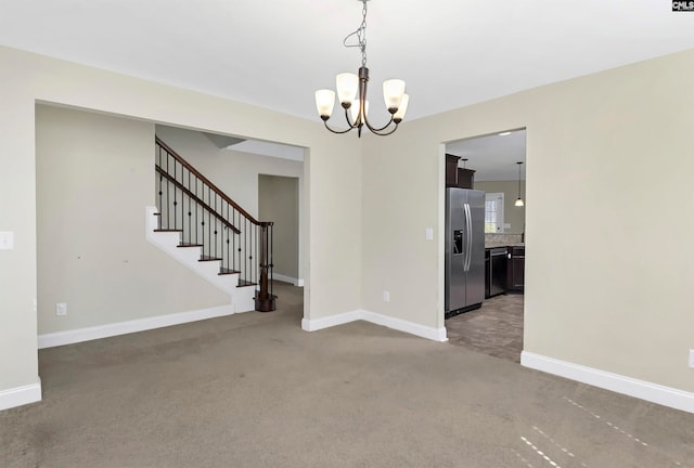 carpeted spare room featuring an inviting chandelier