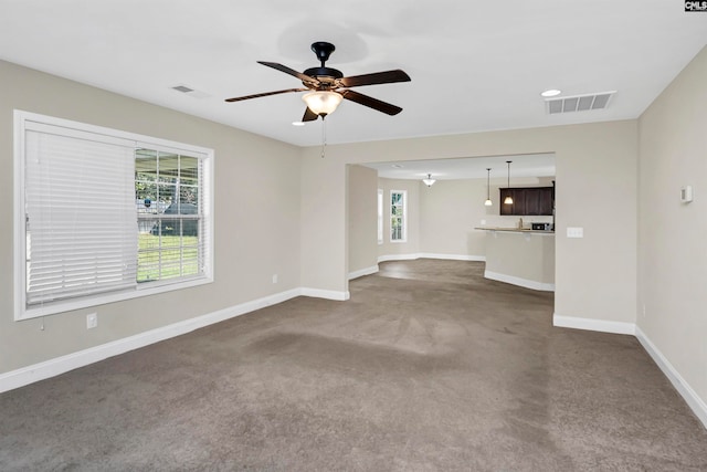 unfurnished living room with ceiling fan and dark colored carpet