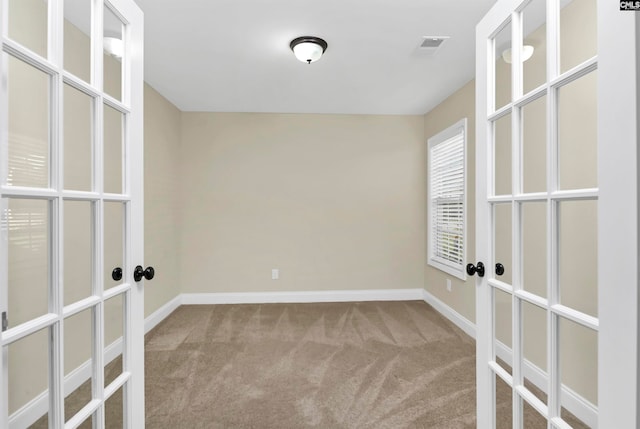 carpeted spare room featuring french doors