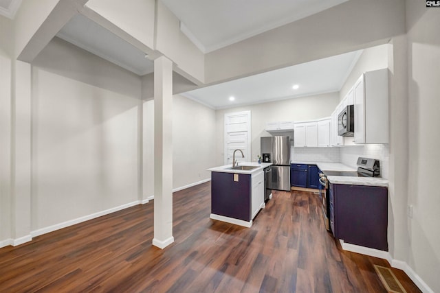 kitchen with tasteful backsplash, blue cabinets, white cabinetry, stainless steel appliances, and a kitchen island with sink