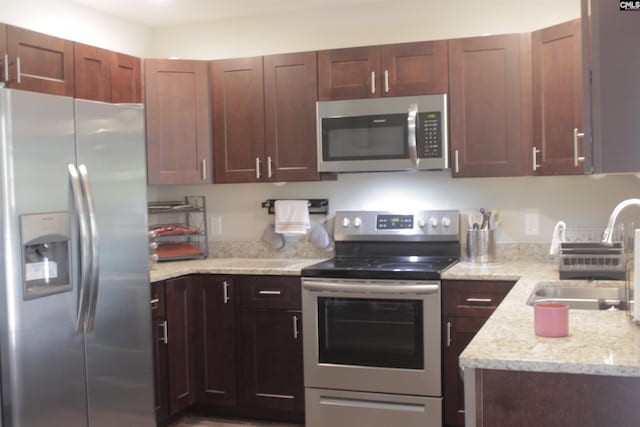 kitchen with light stone countertops, appliances with stainless steel finishes, and sink