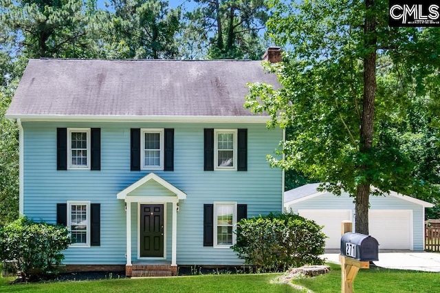 colonial-style house featuring an outdoor structure, a front yard, and a garage