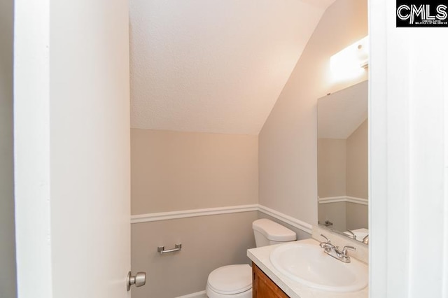 bathroom with vanity, toilet, and vaulted ceiling