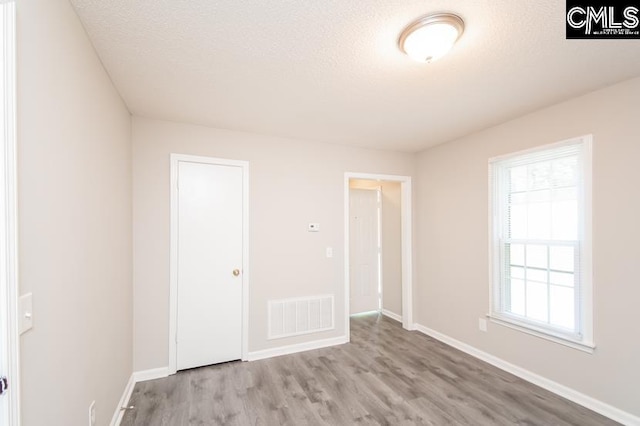 unfurnished bedroom with light hardwood / wood-style floors and a textured ceiling