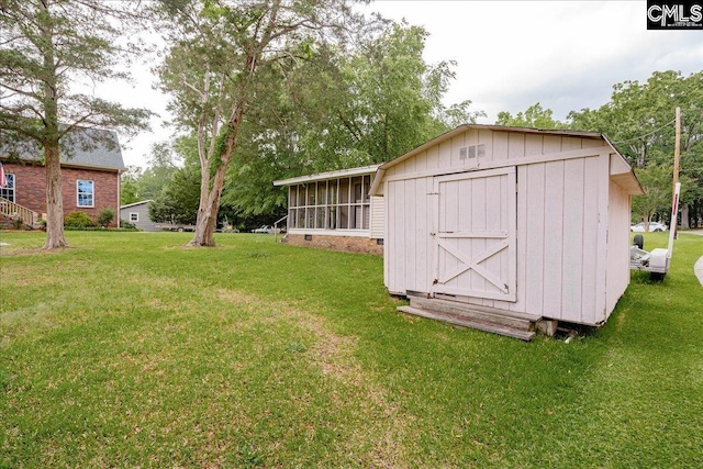 view of outdoor structure with a yard and a sunroom